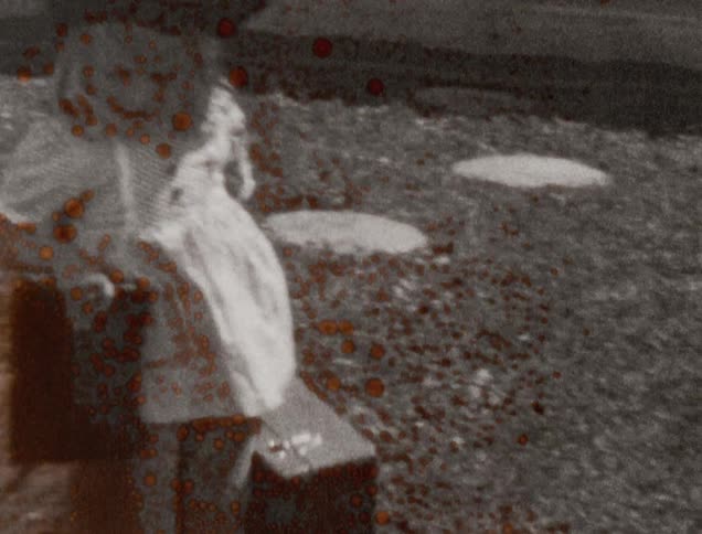 Damaged black and white vintage film of girl playing with suitcase in the lawn