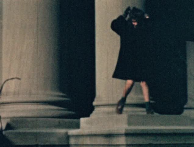 A brother and sister climb up a building by a large column