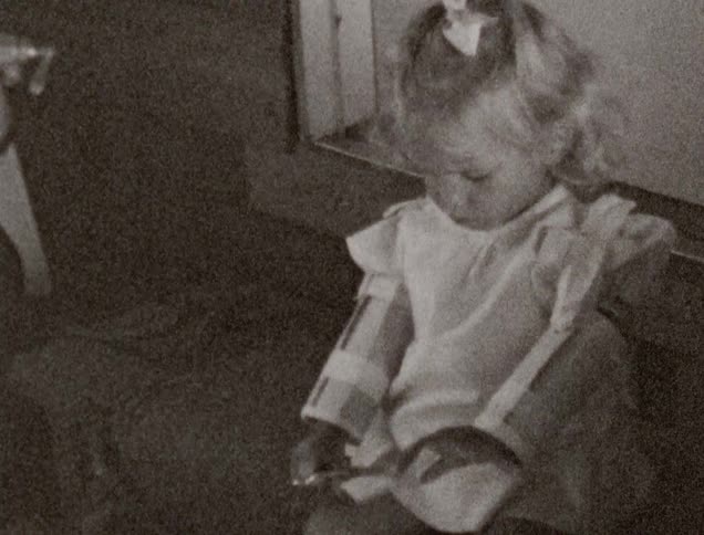 A young sits on her steps of house and cuts paper