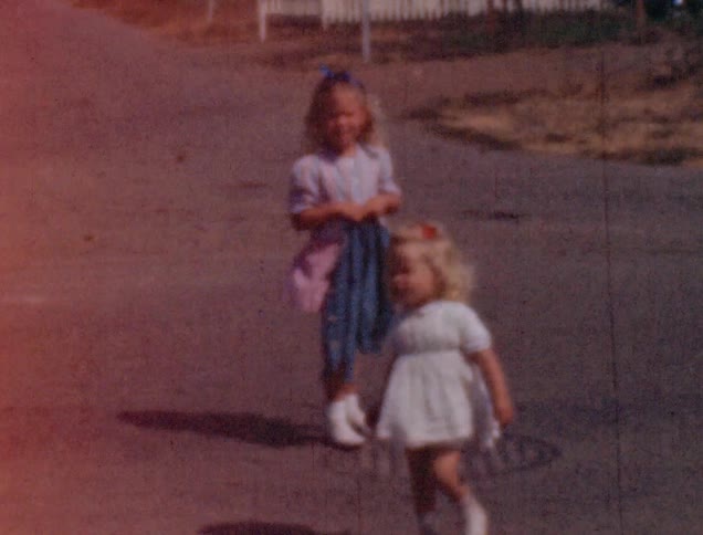 Two girls hold hands in the street