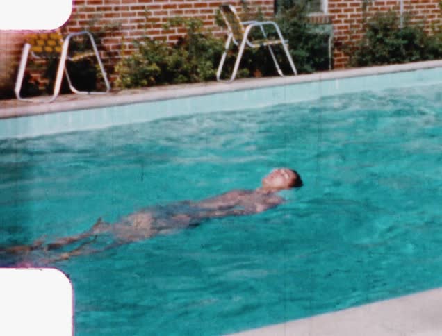A teenager swims on his back in a public pool