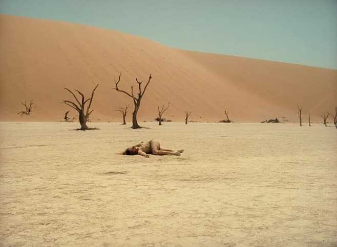 A teenager lies on the soil in a desert