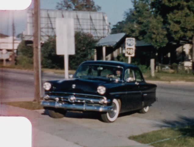 Man wearing a military uniform and driving an old car pulls up and stops the car