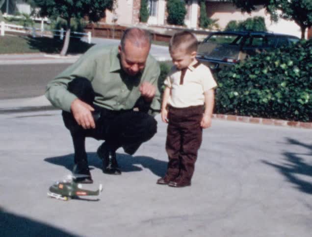 Vintage film of grandfather and grandson playing with a toy in the porch