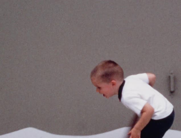 A little boy swings a bat and misses the ball and then his brother passes it to him