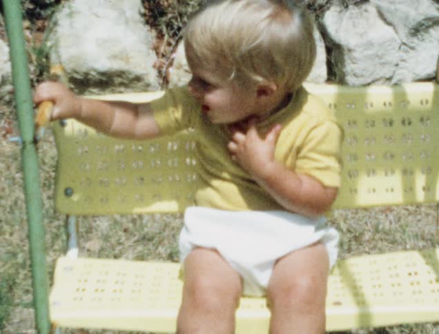 An infant sits in a swing and laughs