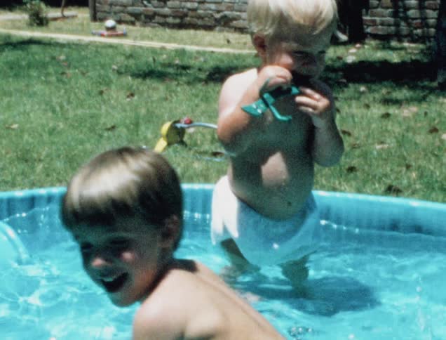 Two young white boys splash in a shallow swimming pool together