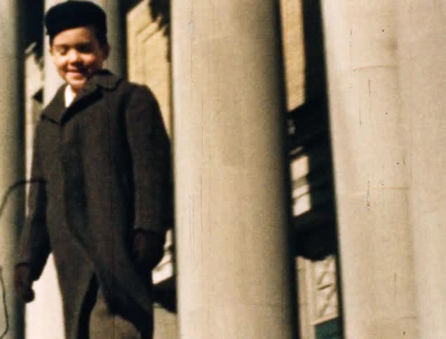 Vintage film boy wearing a coat jumping on a family trip