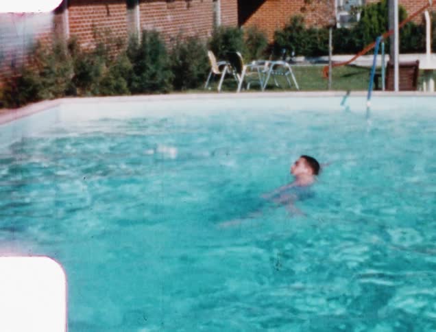A man swimming in a pool outside of a house