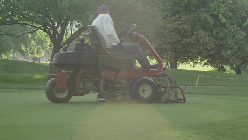 A man drives a riding lawn mower