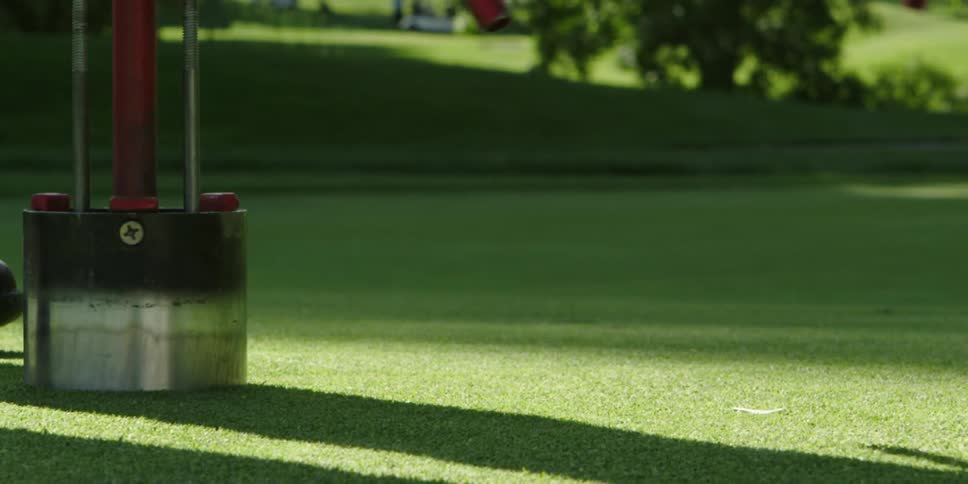 Person makes a hole with a tool on a golf course