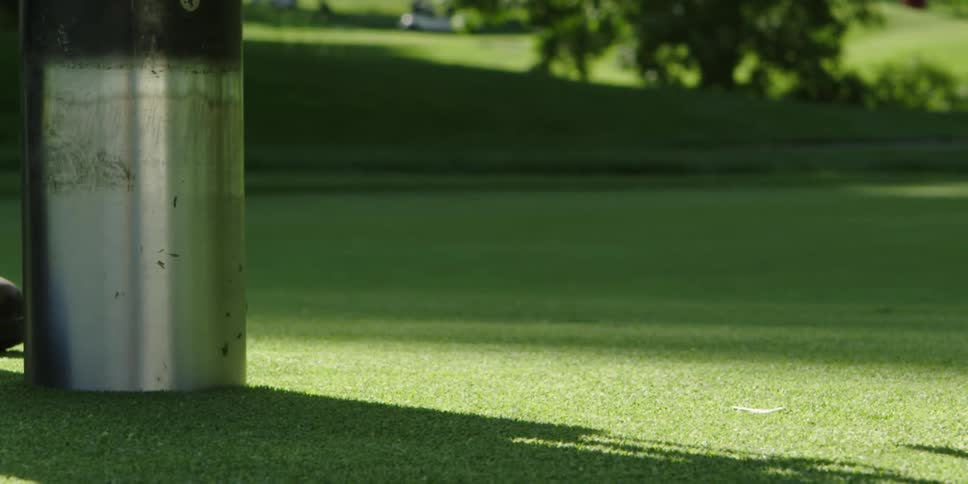 A metal cylinder being extracted from a golfing green by a machine