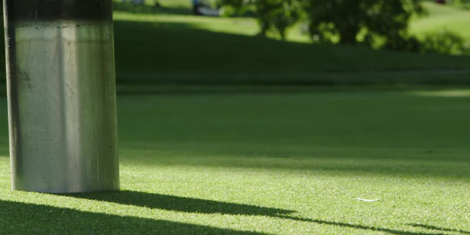 A tool is placed on a golf course to cut a hole in the grass