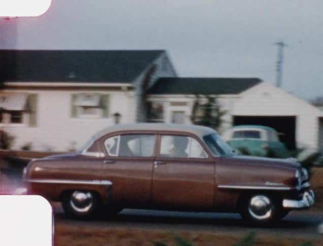 A car driving on the road with houses in the background