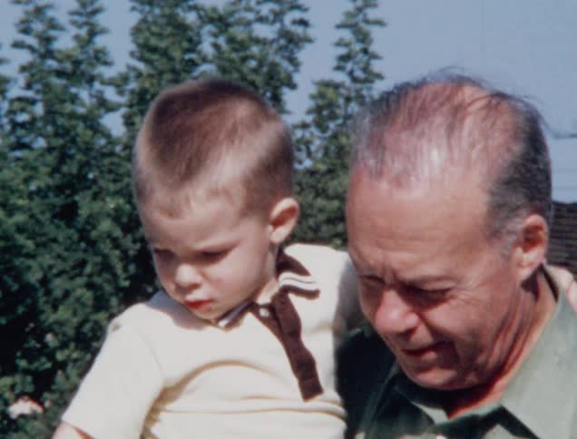 A grandfather holds his grandson and gives him a kiss
