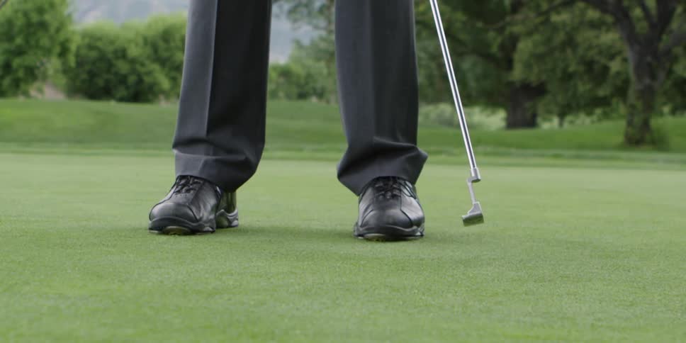Man with black pants plays golf on a golf course