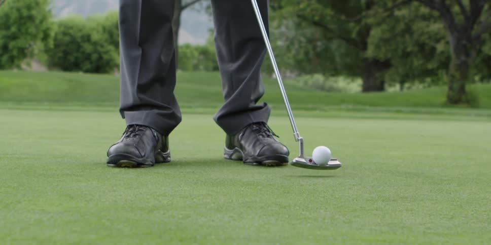 A man hits a golf ball with his club