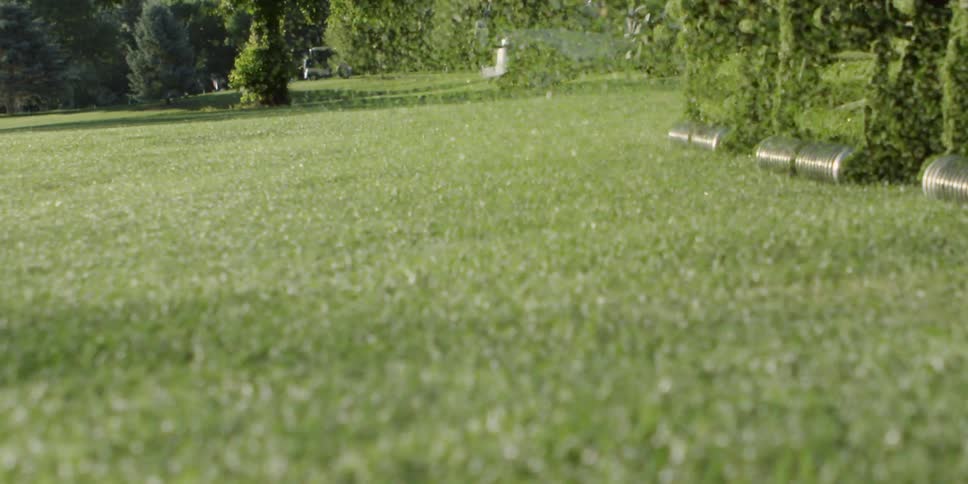 A large mower cuts the grass on a golf course
