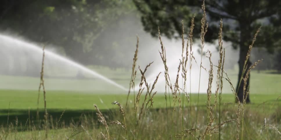A sprinkler running on a golf course