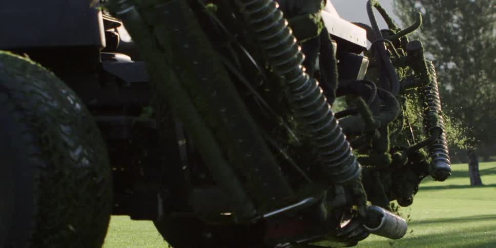 A person driving a heavy duty lawn mower through a large field