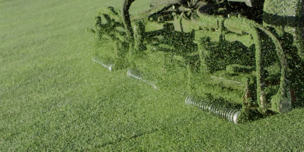 A large mower cuts grass on a big lawn