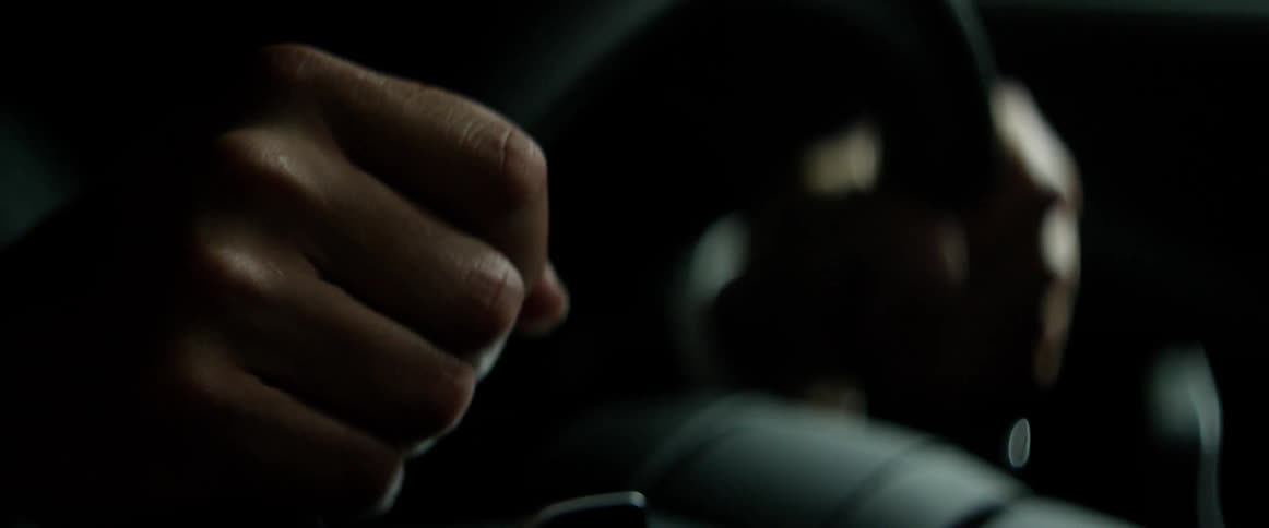 Person inside a car holding onto a steering wheel