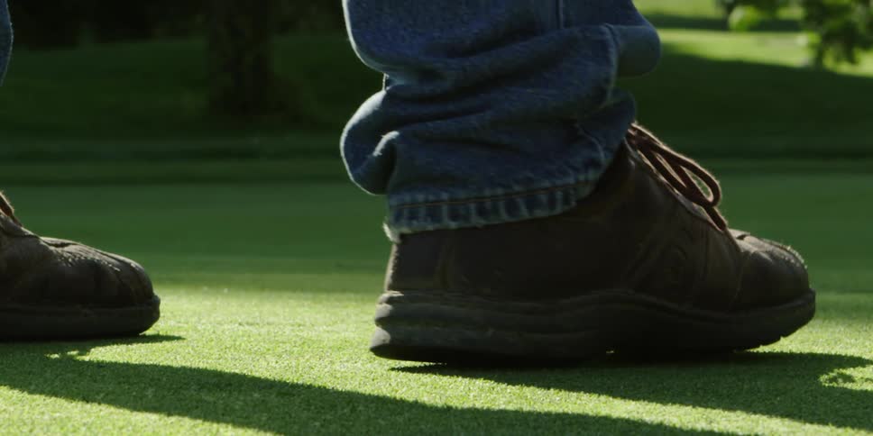 A man steps on a hole on a golf course