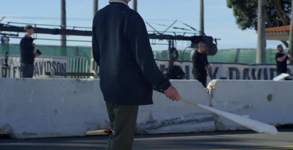 A man waves flags around while waiting for racers to return