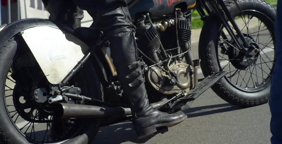 Motorcycle rider attempts to start the motorcycle as someone walks towards him