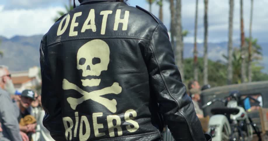 Motorcycle pilot wearing a leather jacket and crash helmet waits on the racetrack