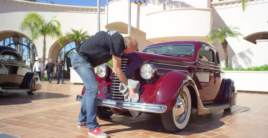 A man is washing vintage red car