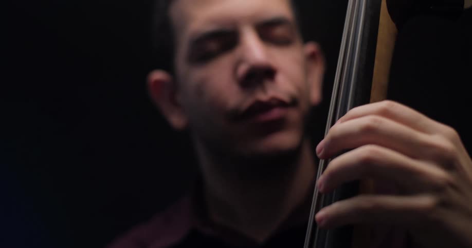 A man closes his eyes and bobs his head as he plays the upright bass