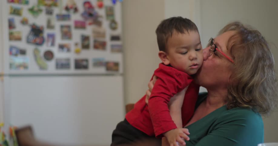 Sitting woman picks up child and kisses him