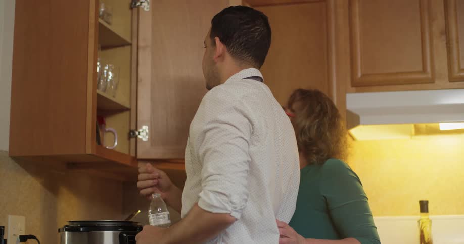 Couple search for utensils in the kitchen cupboard
