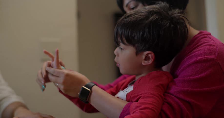 A mother helps her son count on this fingers