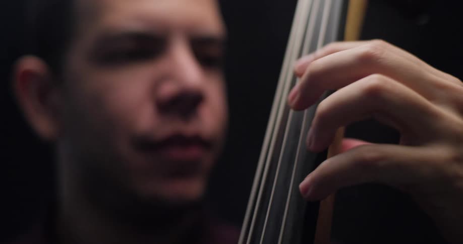Male musician plays the upright bass in stage spotlight
