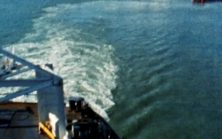 A boat traveling away from a harbor under a clear sky