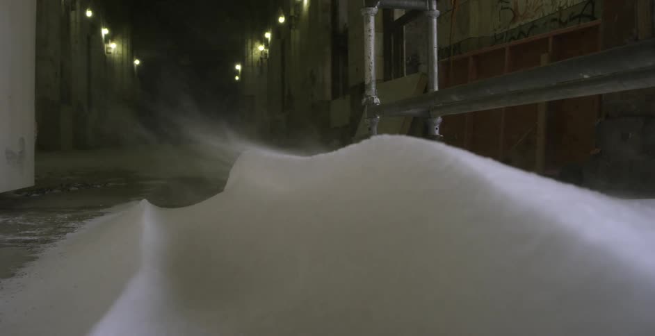 Snow blowing in a street between buildings