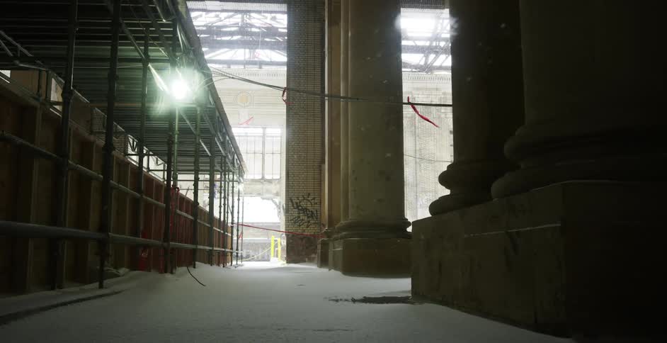 Snow falls through an open roof into an old building undergoing reconstruction