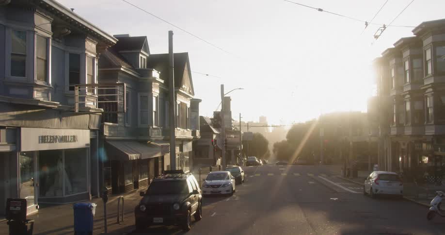 Cars parked along a street that runs through a city neighborhood
