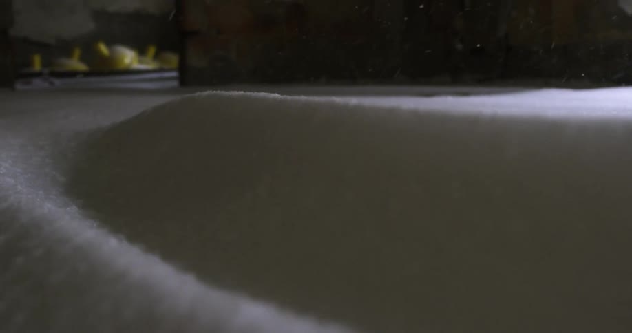 Snow falls into a drift outside a building