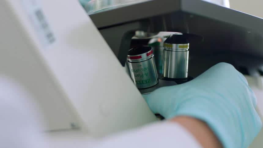 Hand wearing a blue glove turns a device in a lab