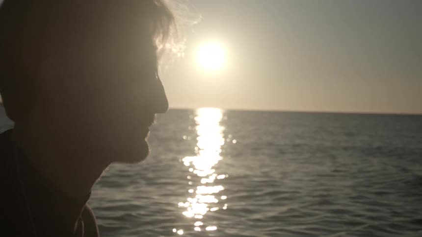 A man looks around the water near sunset