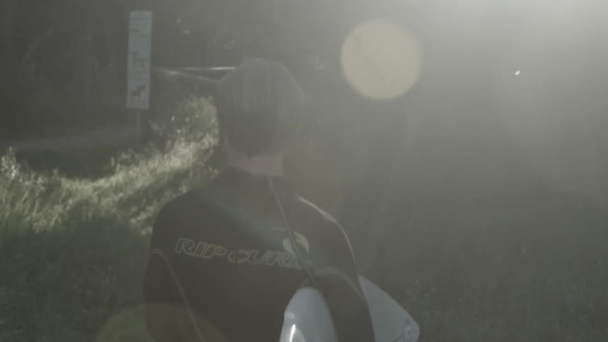 A man in a wet suit walks in the sun
