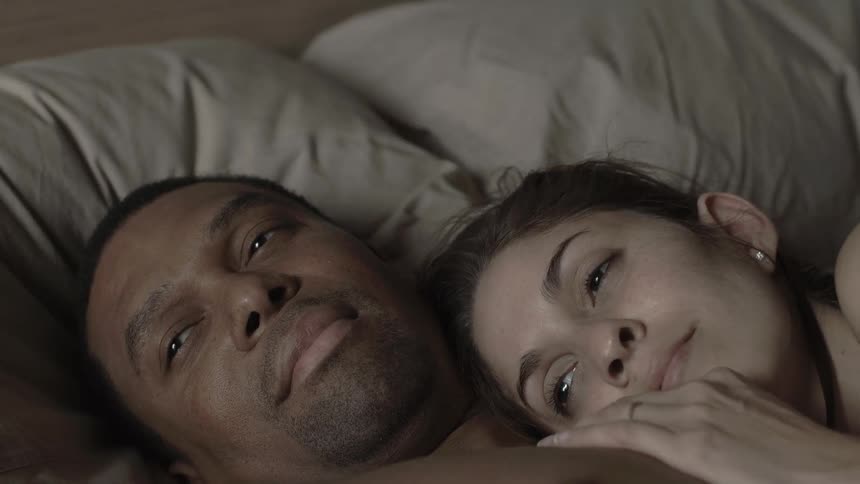 A man and woman snuggling in bed