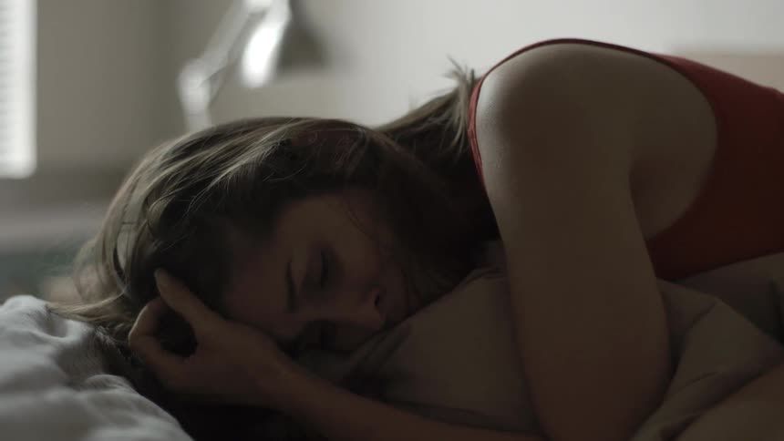 A woman is hugging her pillow as she cries