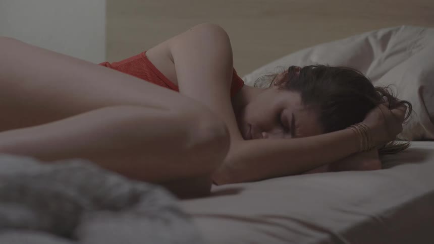 A woman curled up grimaces