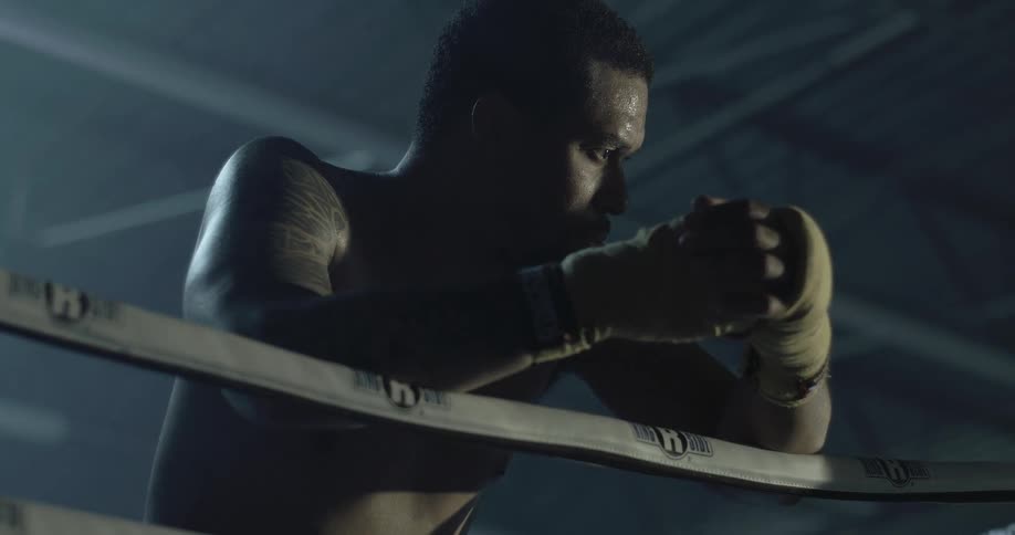 A boxer leaning on the ring ropes