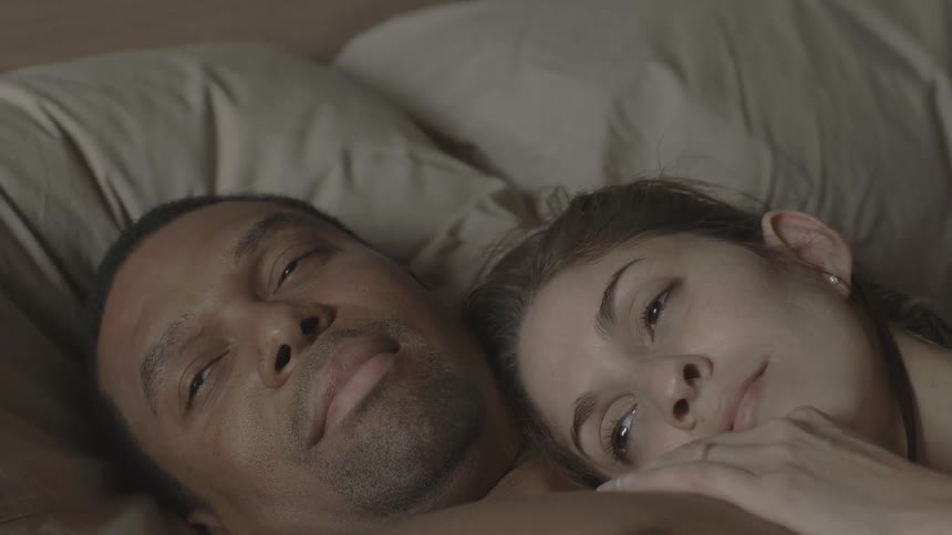 A man and woman snuggle in bed