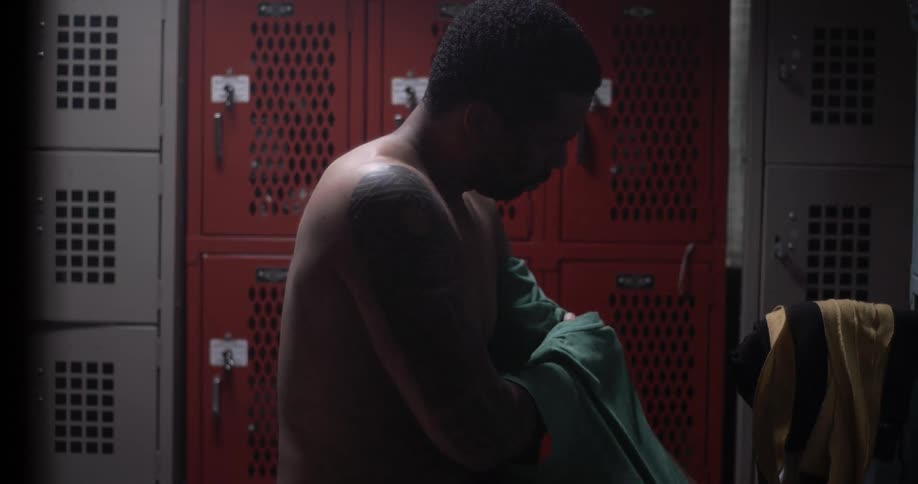 A man removes his shirt in a locker room